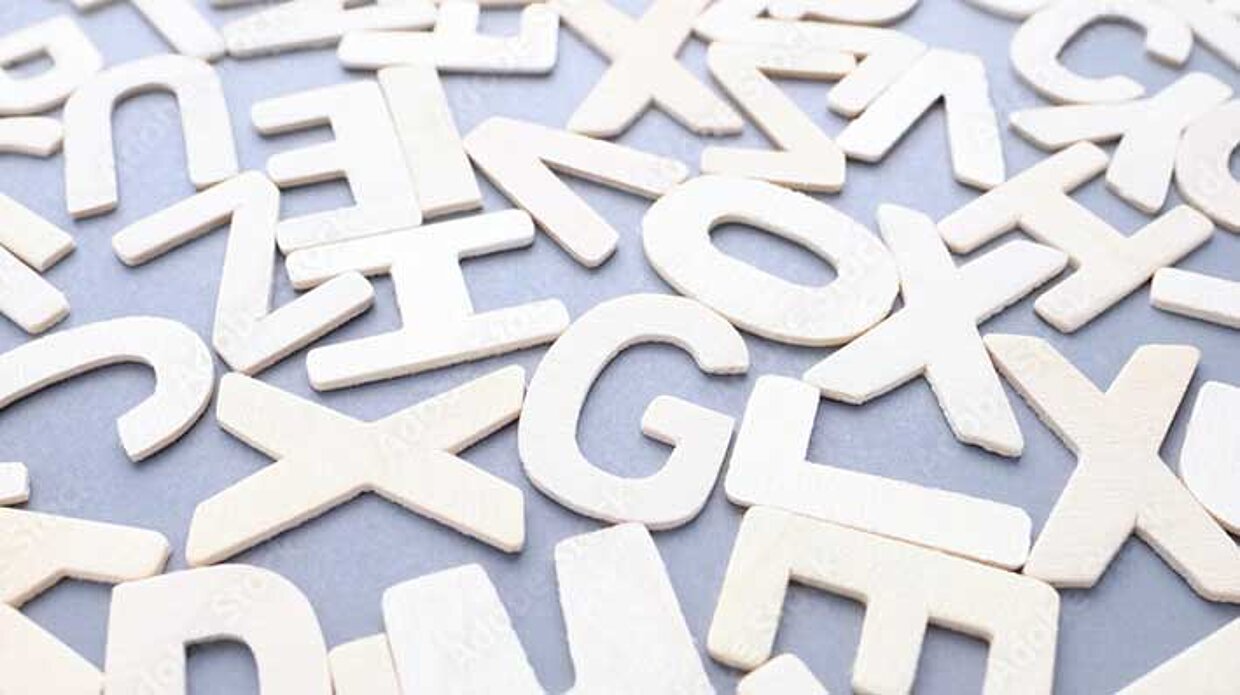 Verstreute weiße Holzbuchstaben auf grauem Hintergrund