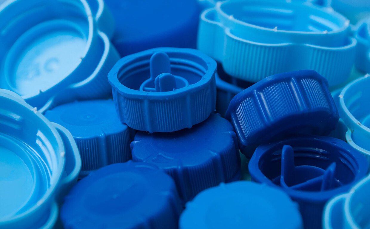 Blick auf eine lose Ansammlung blauer Deckel von Getränkeflaschen