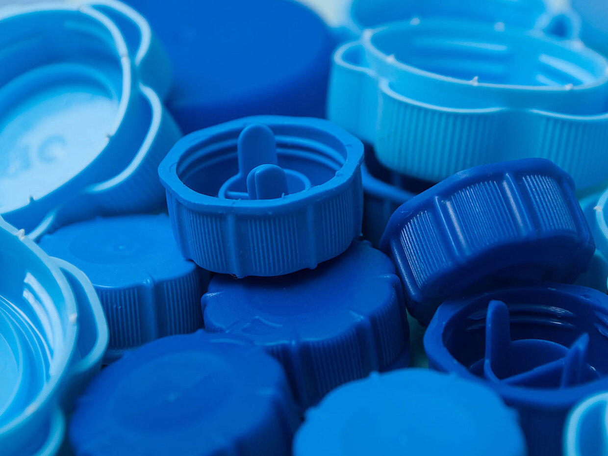 Blick auf eine lose Ansammlung blauer Deckel von Getränkeflaschen